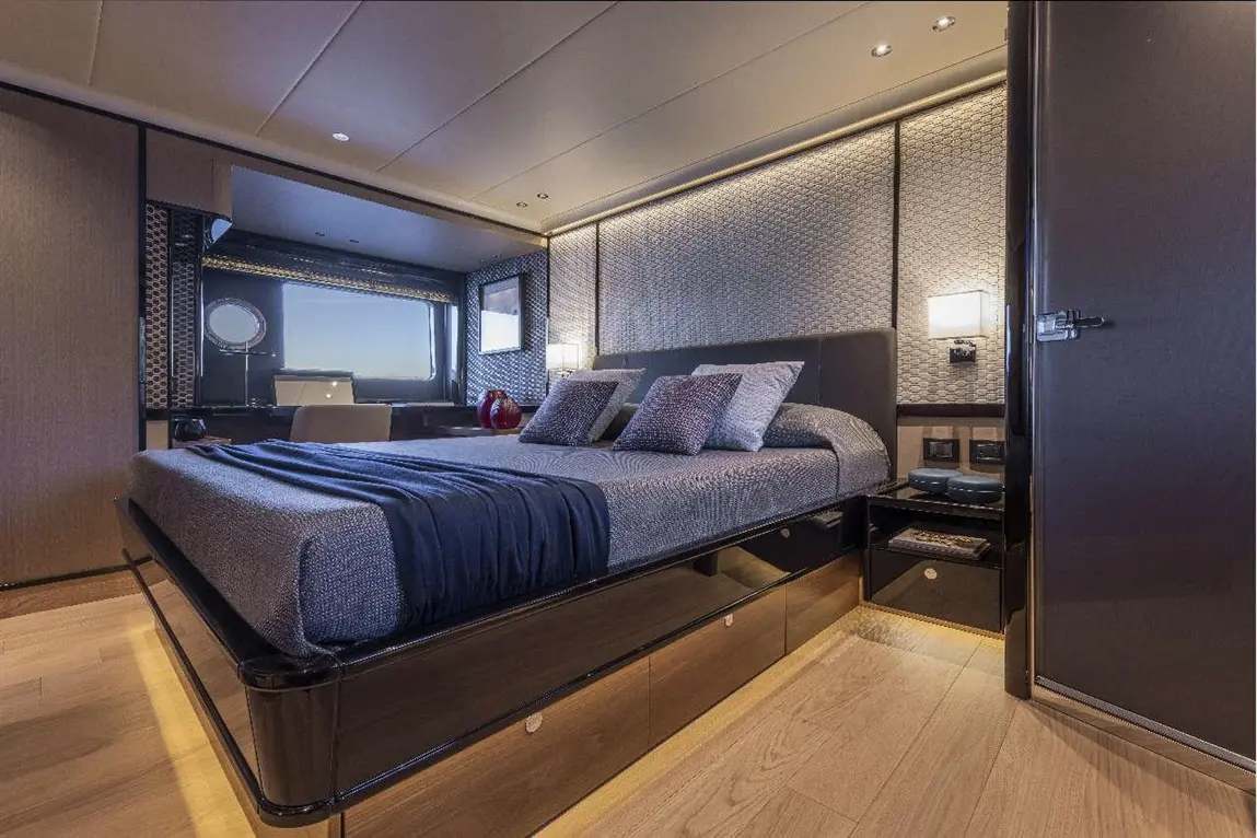 Modern yacht bedroom featuring a large bed, patterned wall, and sea view window, with stylish lighting and sleek furnishings.